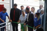 várias pessoas segurando uma faixa verde, para cortar, que marca a inauguração